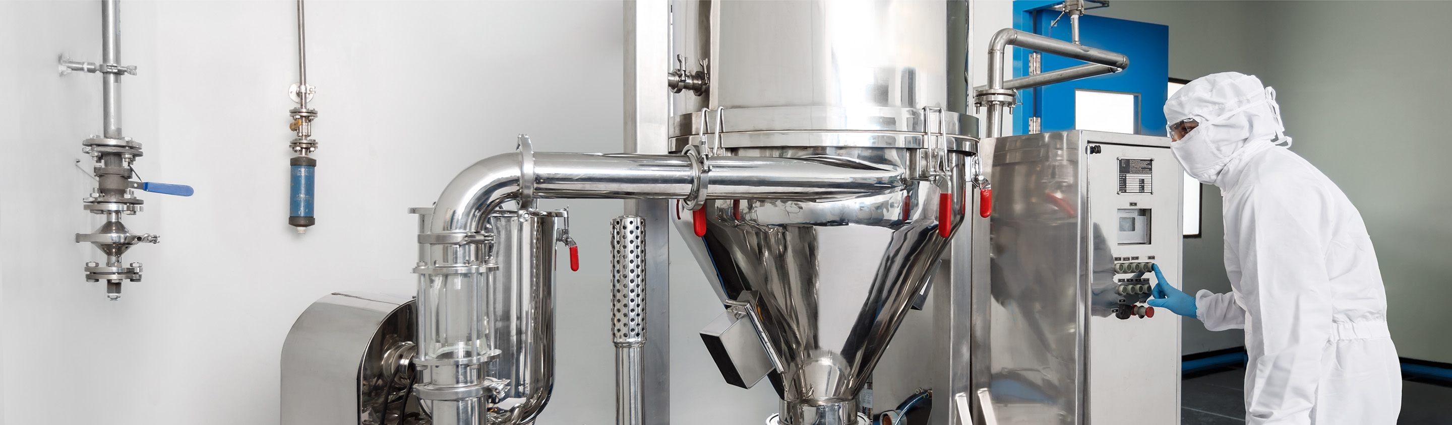 Stainless-steel process piping and vessel in an Aragen custom chemical synthesis plant with an operator in cleanroom gear