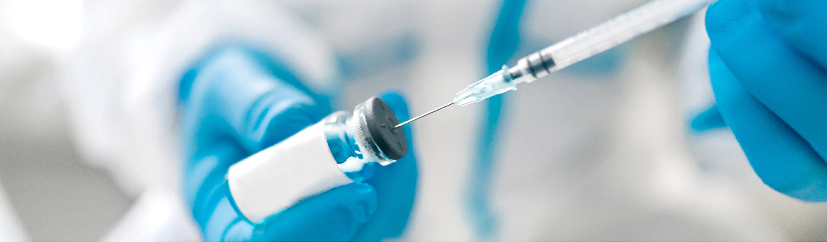 Gloved hands drawing liquid from a vial with a syringe for extractables and leachables testing