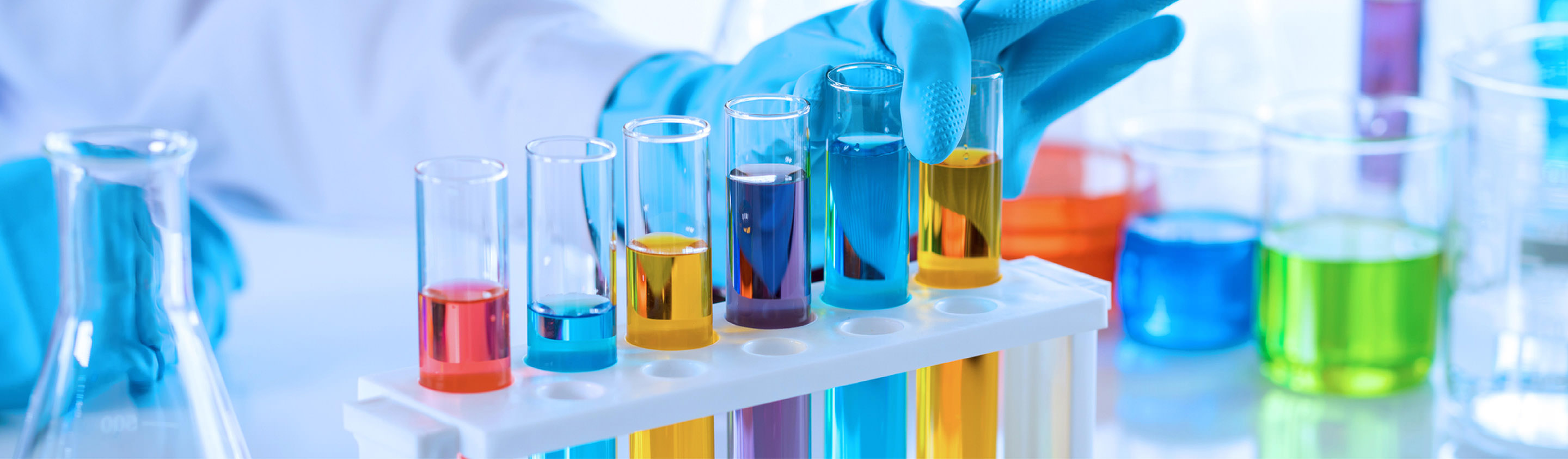 Row of test tubes and flasks filled with brightly coloured chemical solutions