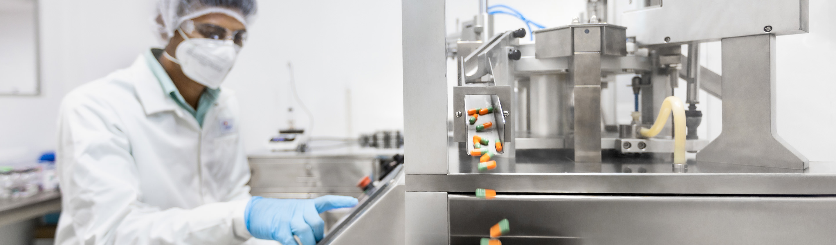 Aragen technician in gown and mask operating a drug product formulation and filling line