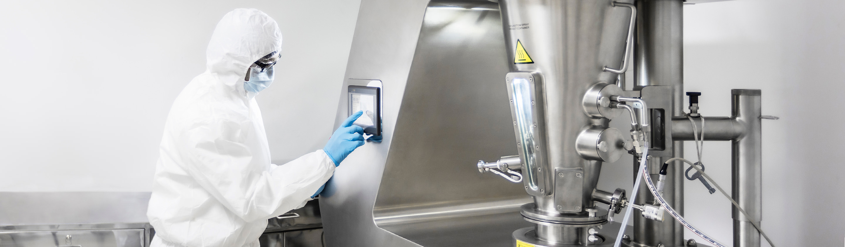 Operator in cleanroom suit operating a pharmaceutical preformulation processing machine