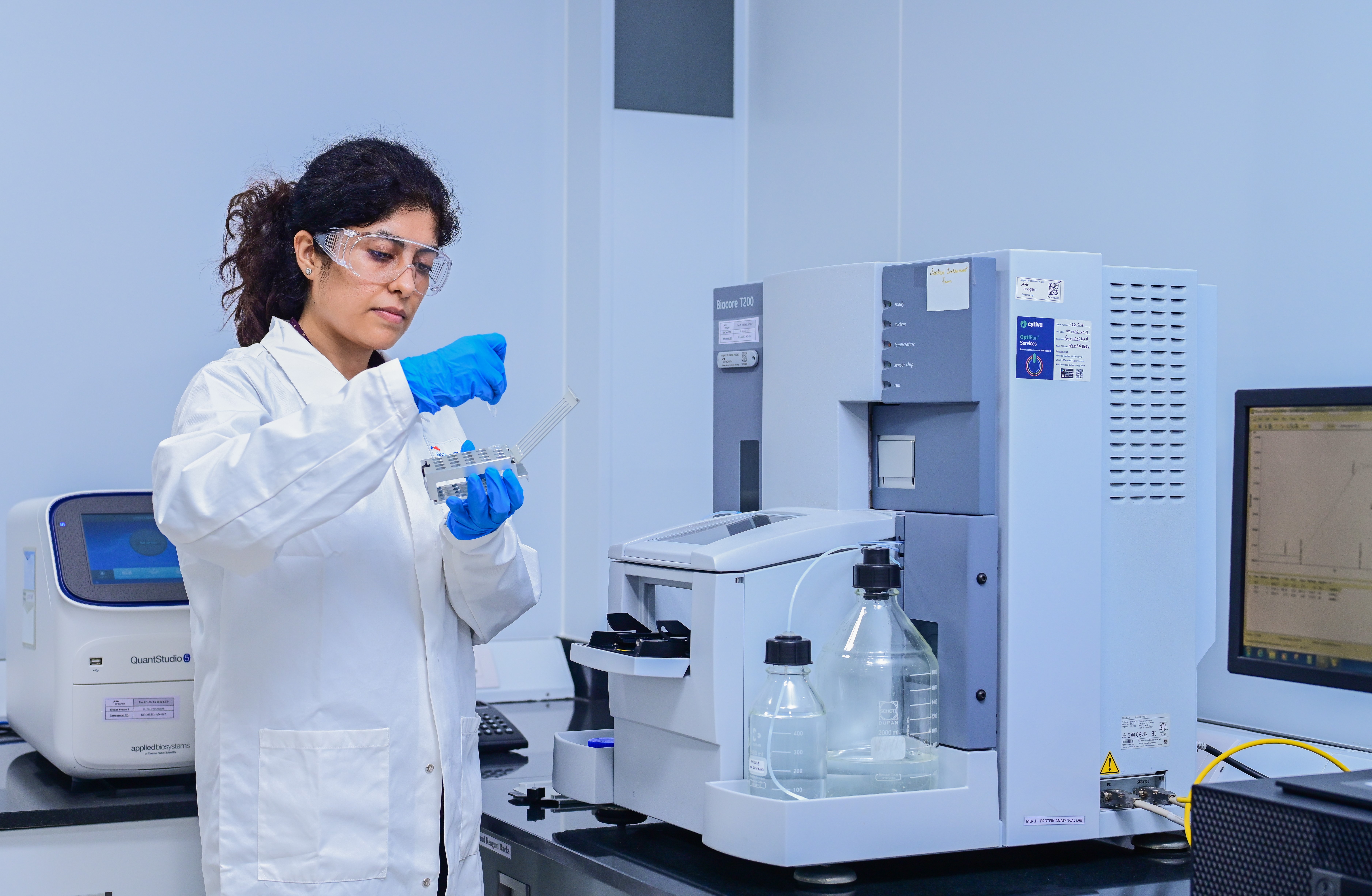 Aragen scientist in safety glasses and gloves preparing a sample beside analytical instruments in a protein characterization lab