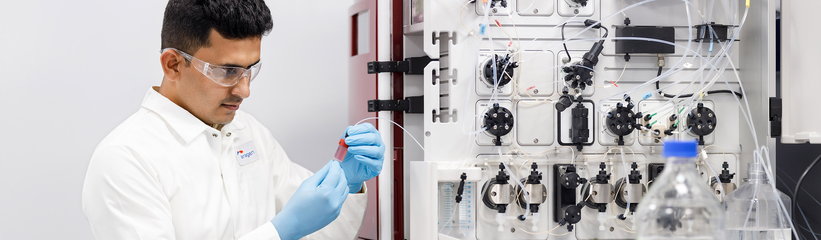 Aragen scientist in safety glasses operating a protein chromatography system