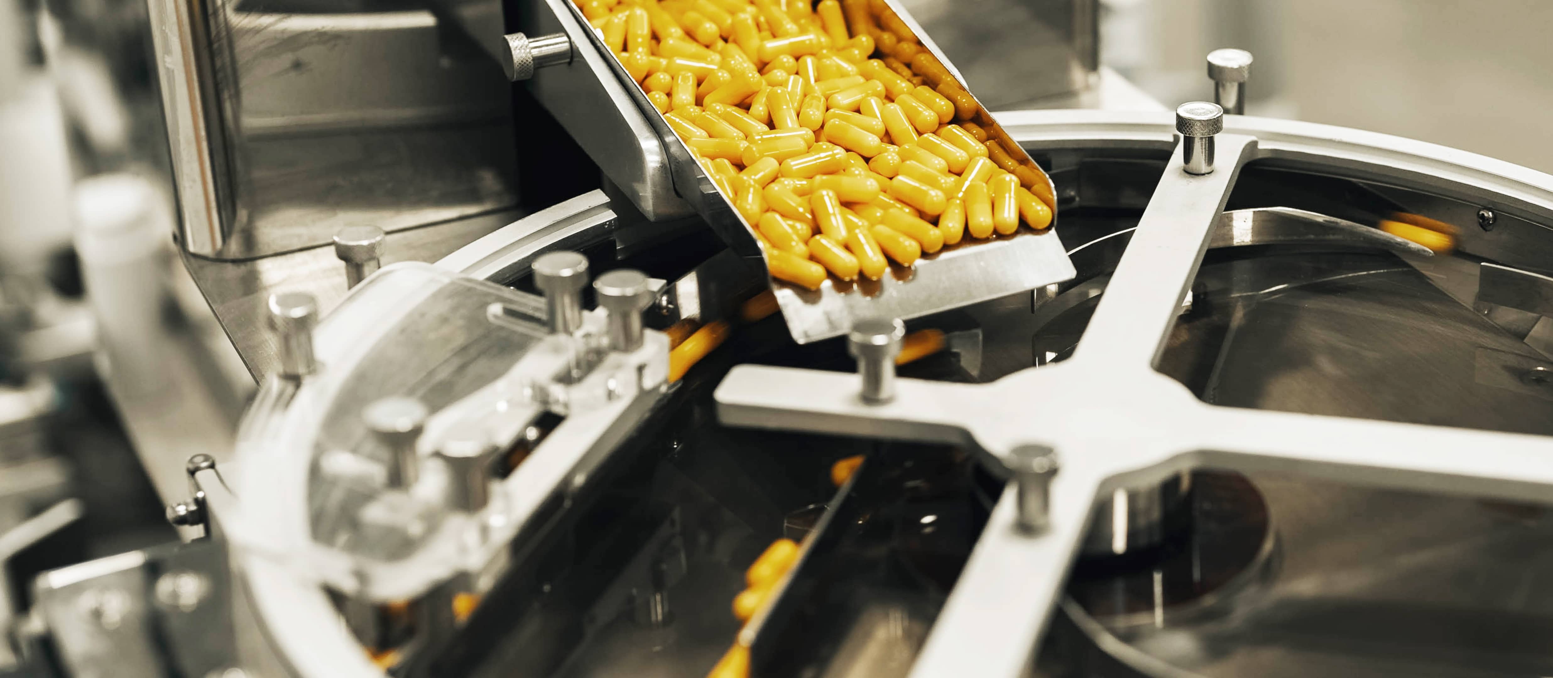 Yellow capsules being discharged from a capsule filling machine in a formulation development facility