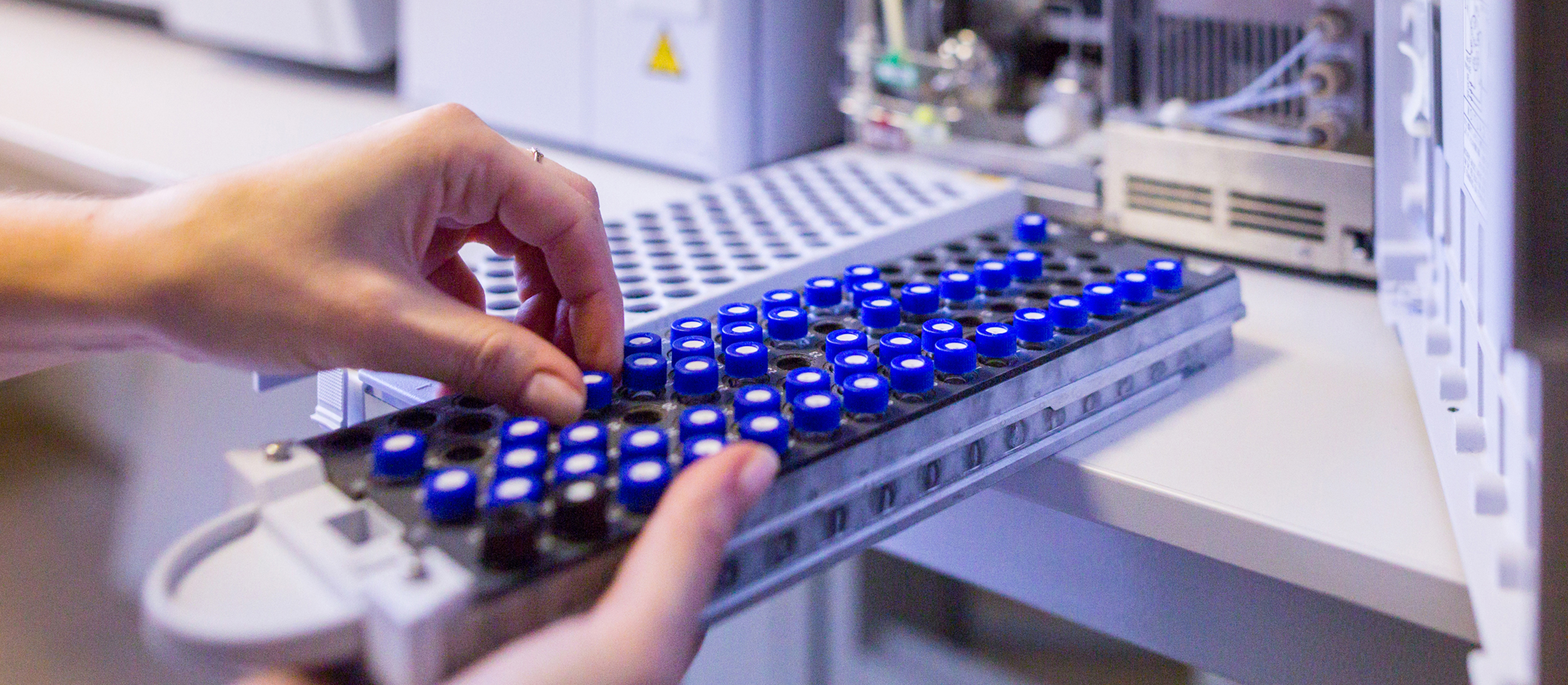 Analyst loading vials into an HPLC autosampler tray in Aragen's analytical solutions laboratory
