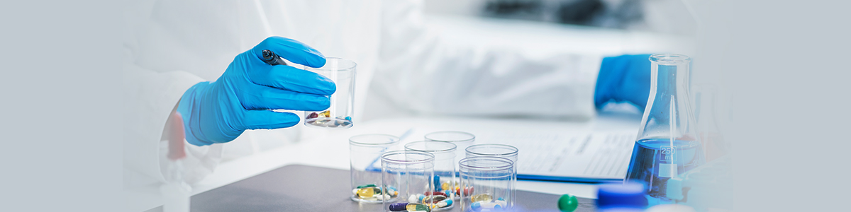 Gloved hand handling sample vials at a laboratory bench, representing IND-enabling services