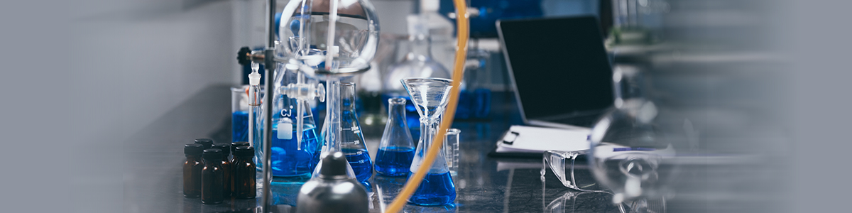 Laboratory bench with glassware, blue solutions and a laptop in Aragen's pilot lab