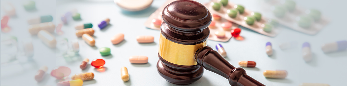 Wooden gavel beside assorted pharmaceutical pills and capsules, representing regulatory support