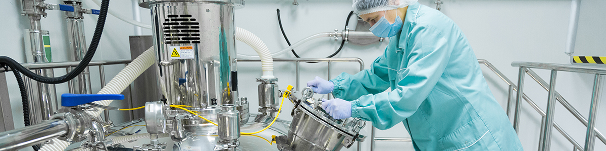 Operator in cleanroom suit working on process equipment, representing process safety and risk management