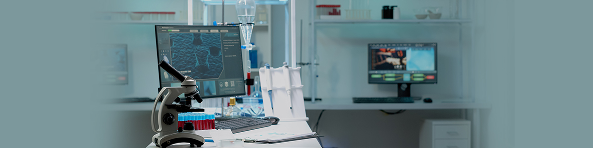 Analyst at a computer workstation beside laboratory instruments, representing technology transfer