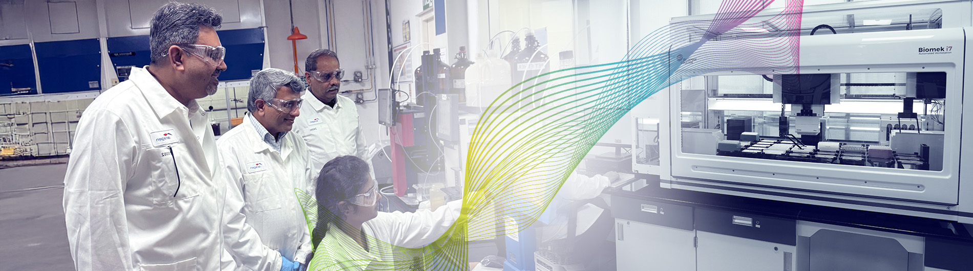 Three Aragen scientists in lab coats reviewing results beside analytical instruments in an integrated drug discovery lab