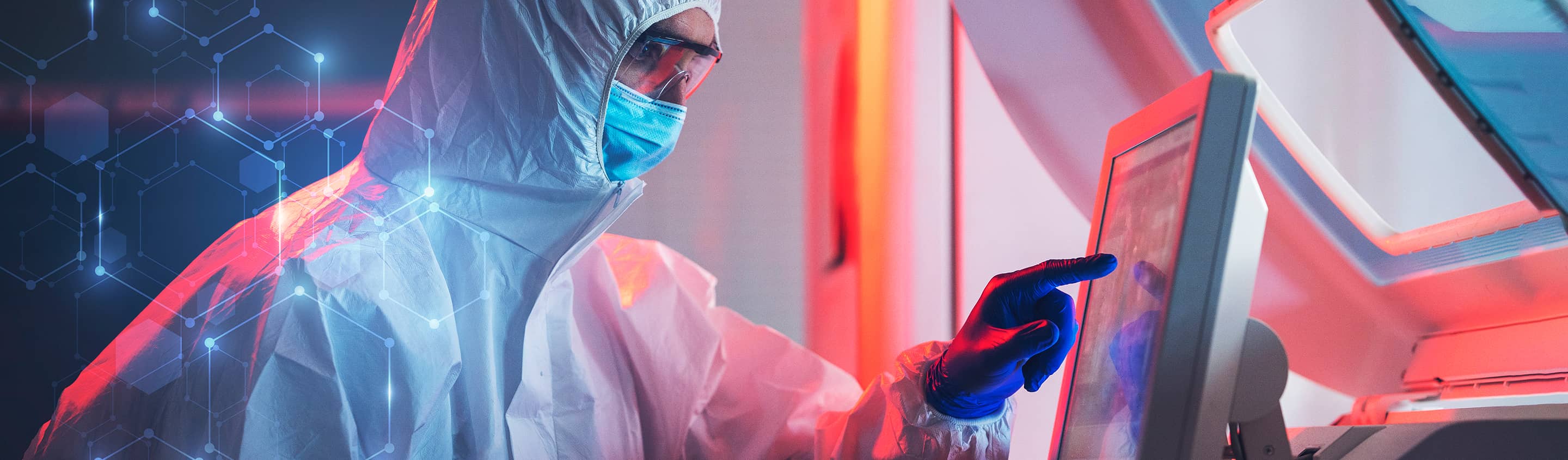 Scientist in cleanroom gown working at a computer screen in a drug discovery laboratory