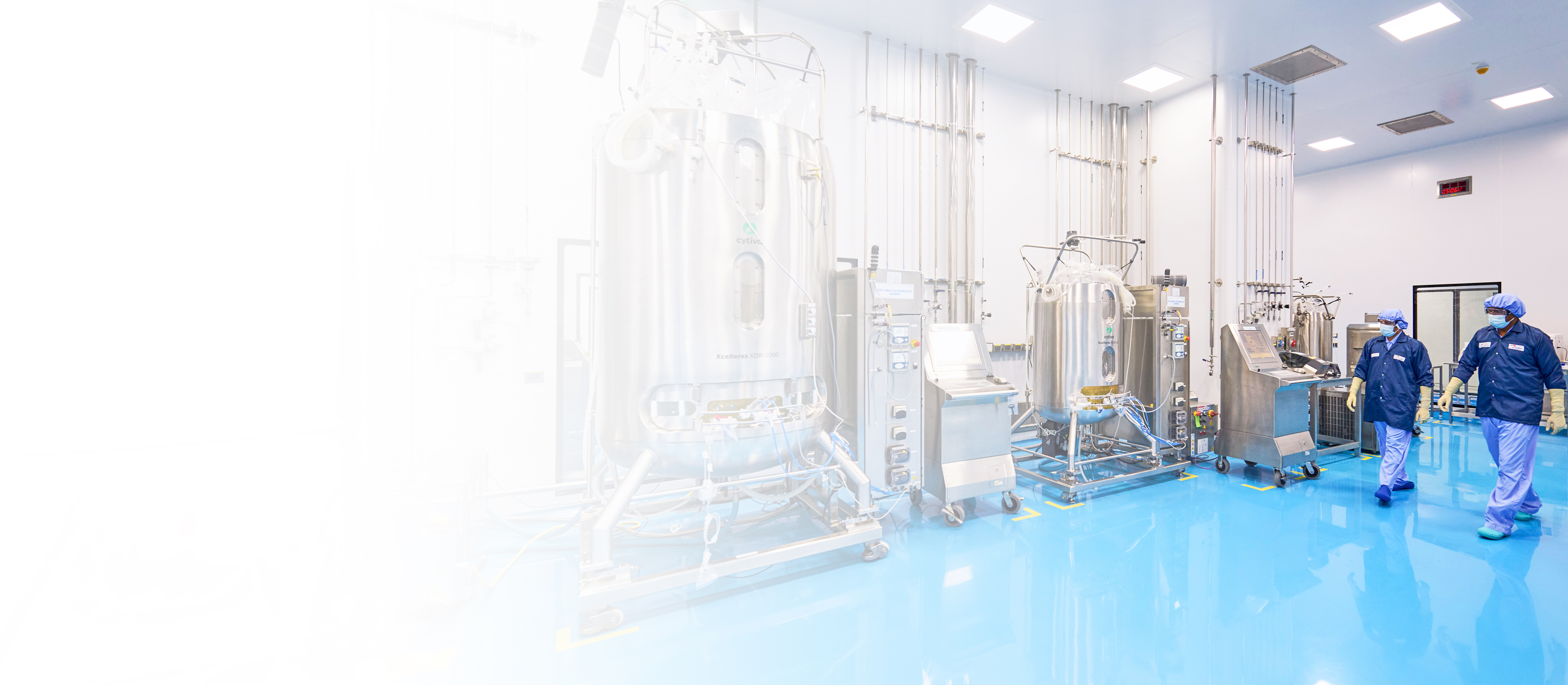Interior of Aragen's biologics manufacturing suite with stainless-steel bioreactors and operators in cleanroom gowns