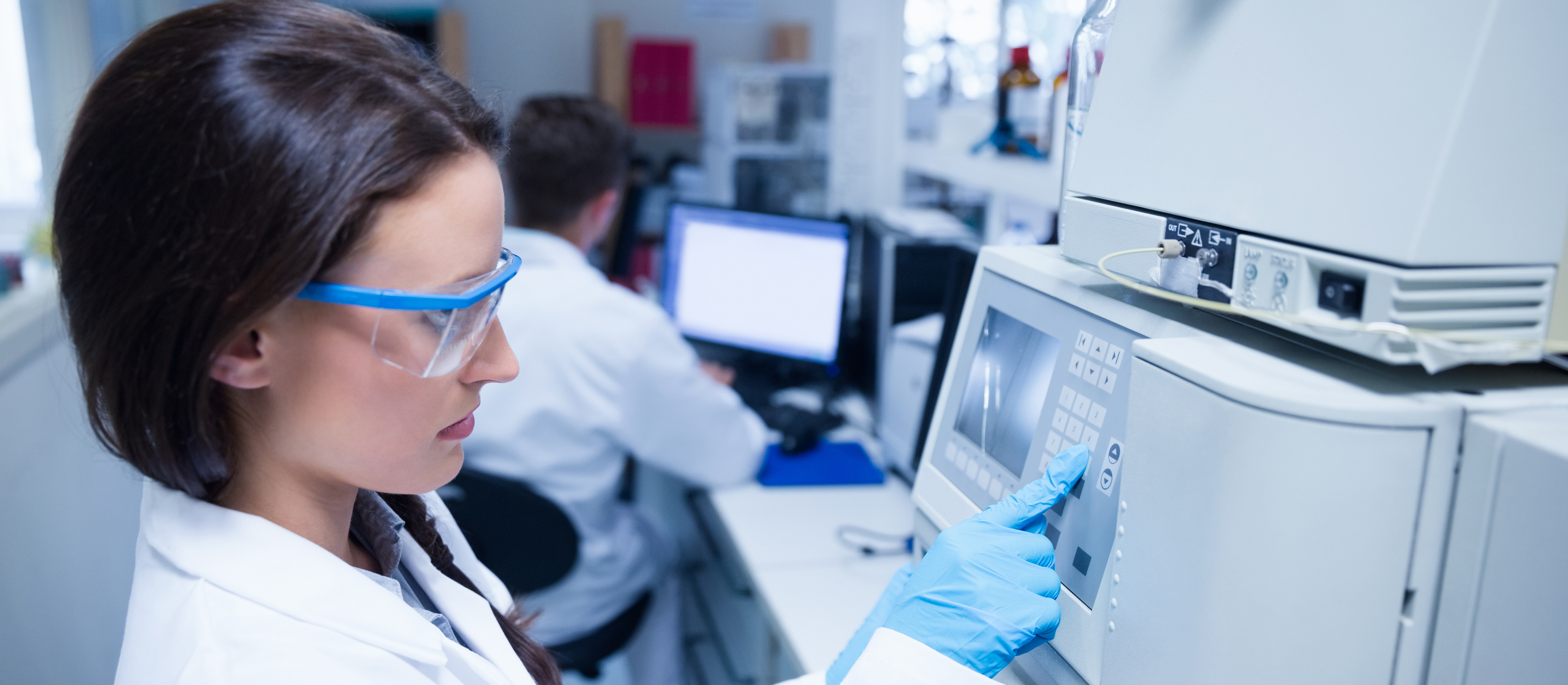 Aragen analyst in safety glasses operating an analytical instrument in the analytical solutions laboratory